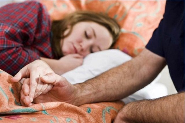 Мужчина держит спящую девушку за руку